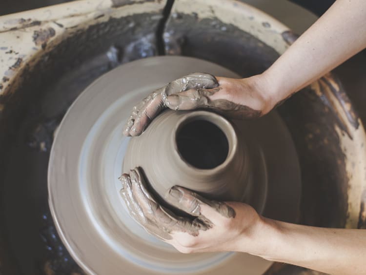 Pair of hands carefully mold a jar of clay