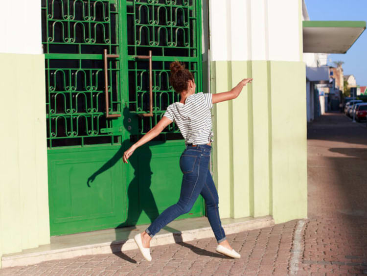 Woman joyfully skips along the sidewalk