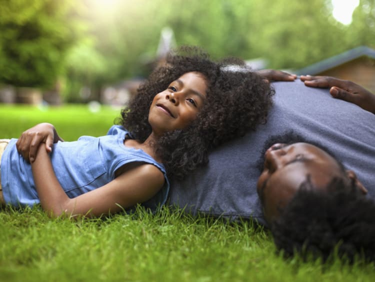 Little girl looking peaceful laying her head on her dad on the lawn