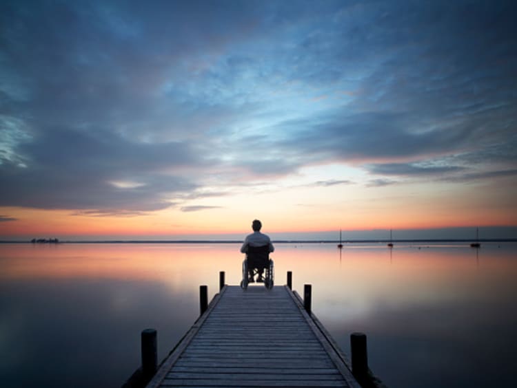 Man looking out at the sunset from dock