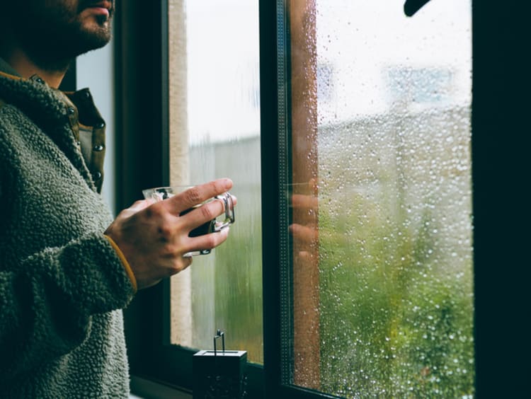 man standing at window having hope in hard times