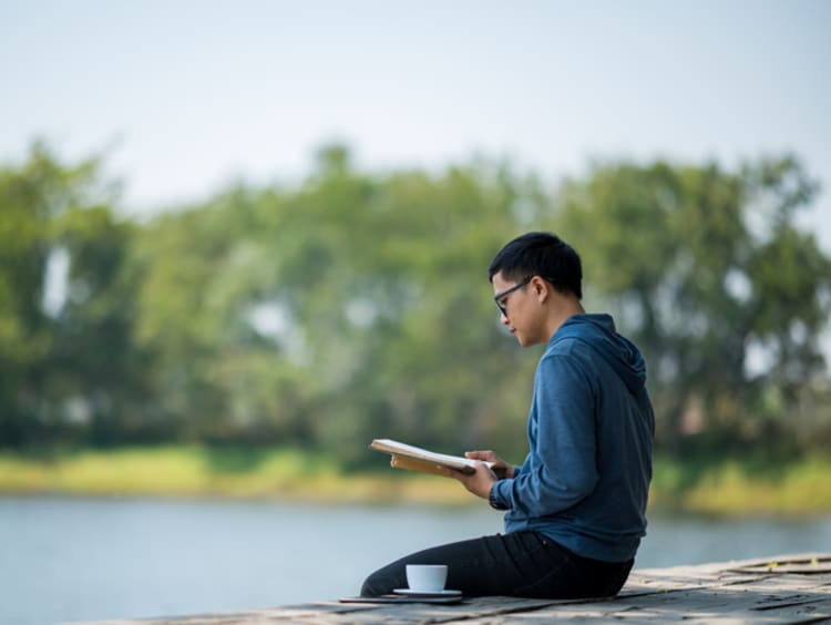 Man reading scripture by lake and making time for God