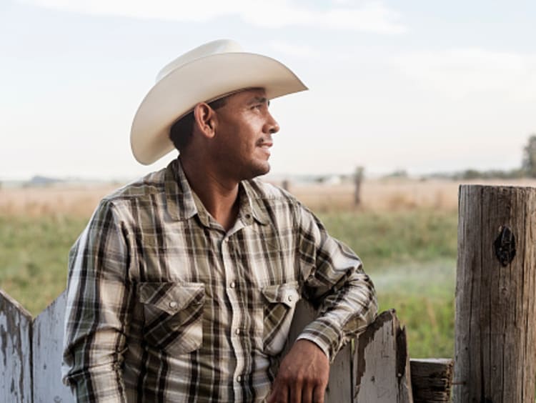 Man standing next to fence looking at field