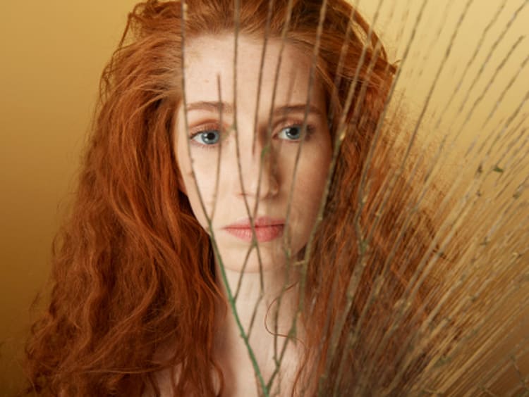 Woman looking in broken mirror