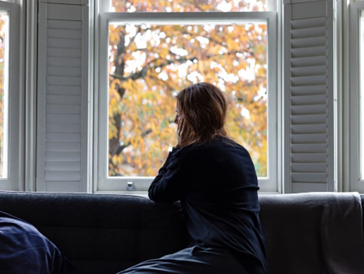 Young woman looking out the window and fighting shame and guilt