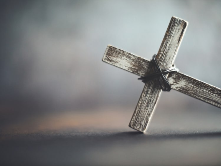 A cross lays on its side with eery smoke looming in the background