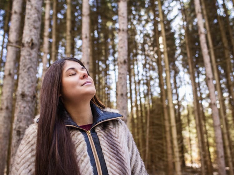 Woman having a spirit of humility while looking up at trees