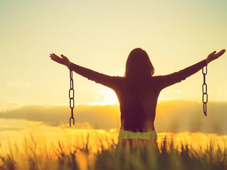 girl in field holding arms out with broken chains