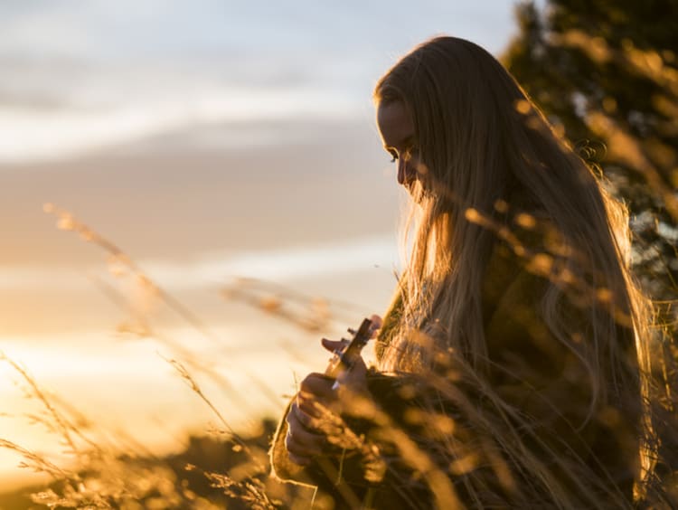 Young woman playing ukulele and worshipping in the early morning sunlight