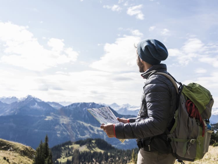 Strong and courageous hiker looking for path on map