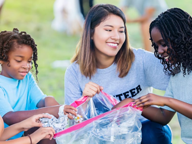 Volunteer leader helping kids clean up trash in park