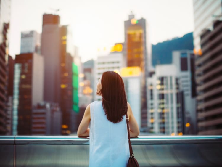 Deep thinking woman gazes out yonder at city skyscrapers