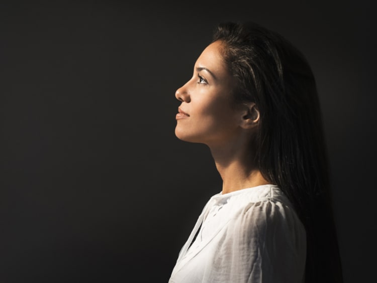 Young woman looks at the light to left with black background