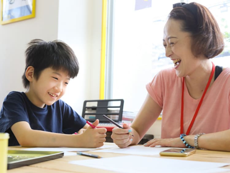 Female paraprofessional laughing and working with young student in classroom