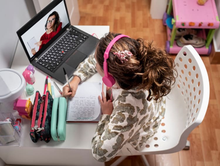 Young student completing lesson with teacher in an online classroom