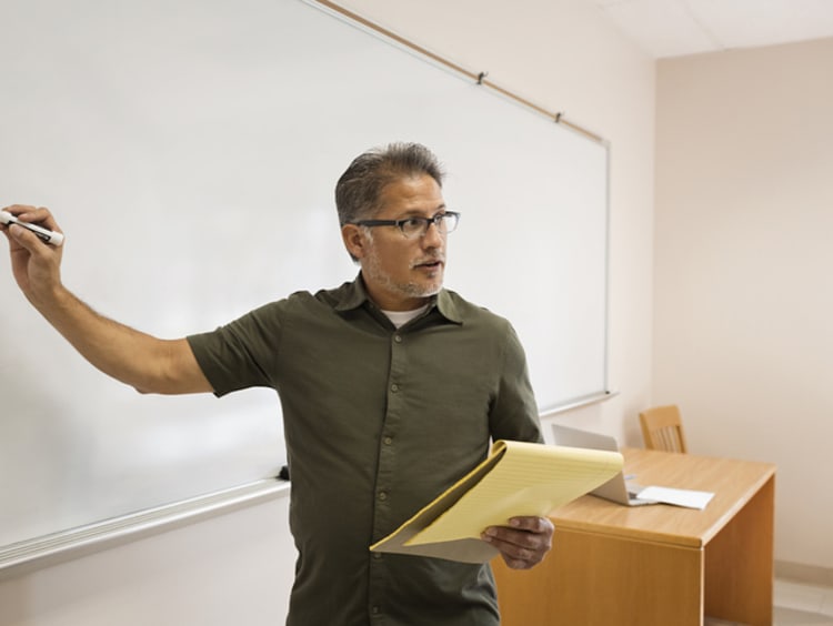 Male teacher writing on whiteboard to teach students how to learn to read