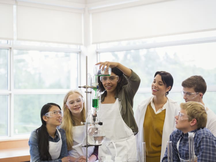 Female STEM teacher working with young students in science classroom