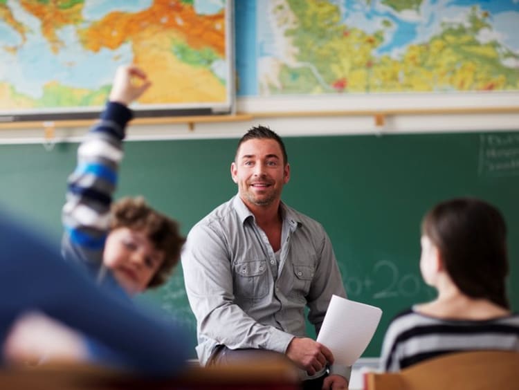 A male teacher calling on a student with his hand raised