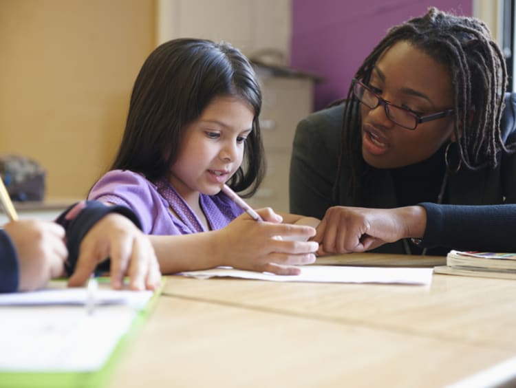 A female teacher helping a young student with class work