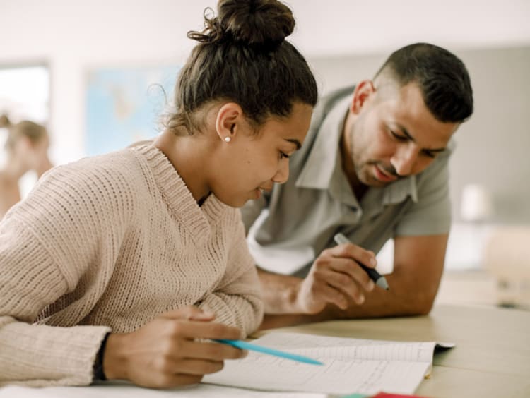 female student and male teacher reading together in classroom