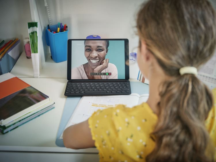 African-American female teacher laughs on young female student's laptop screen