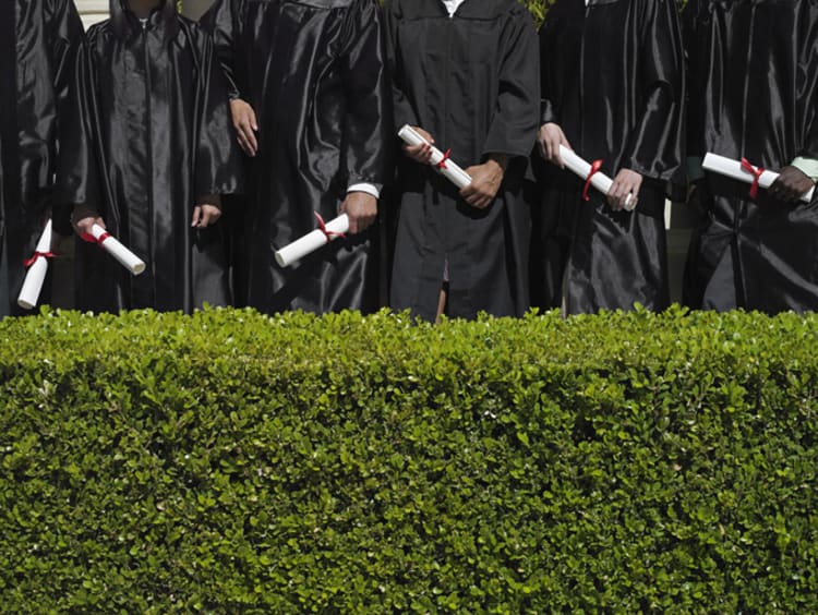 Education graduates in their gowns holding diplomas