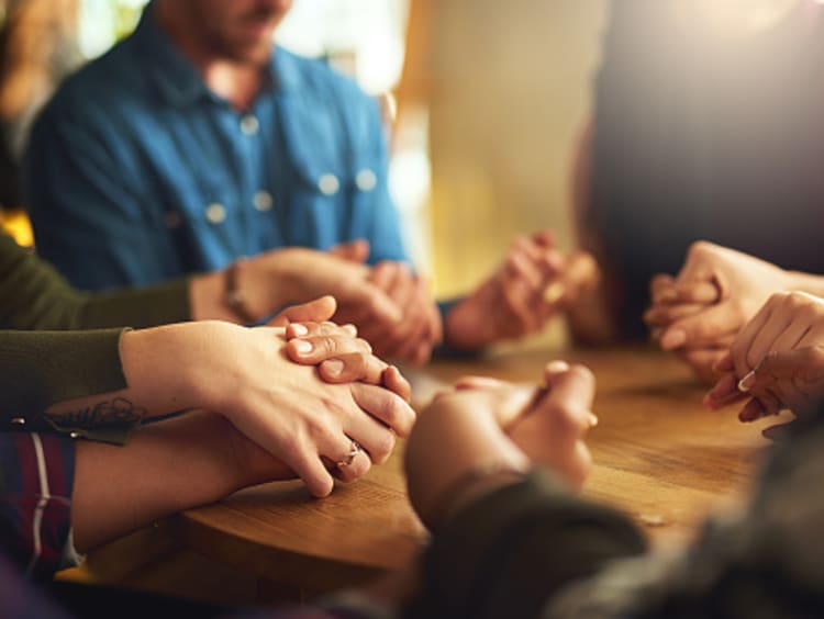 Christians engage in community by holding hands in prayer