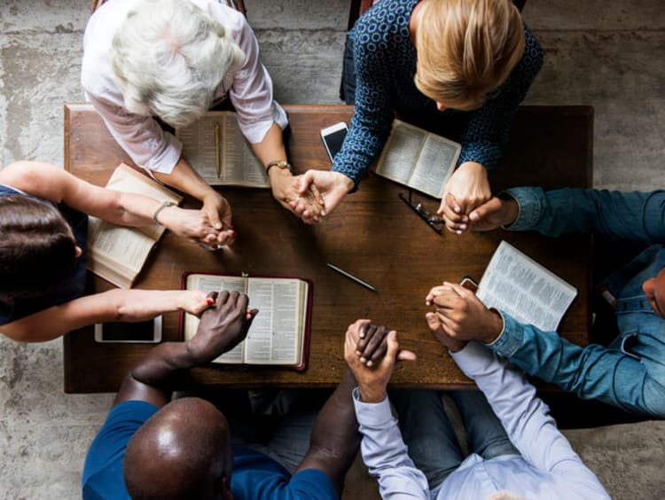 Group of people sitting at a table and praying