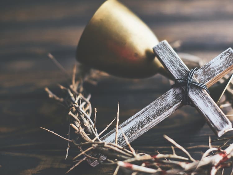 A cross lays with a crown of thorns and chalice