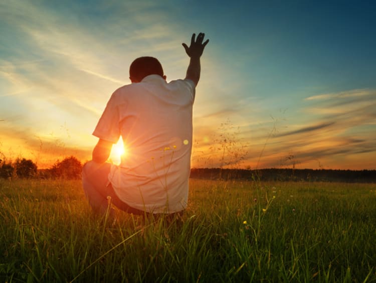 Man prays to God in grassfield 