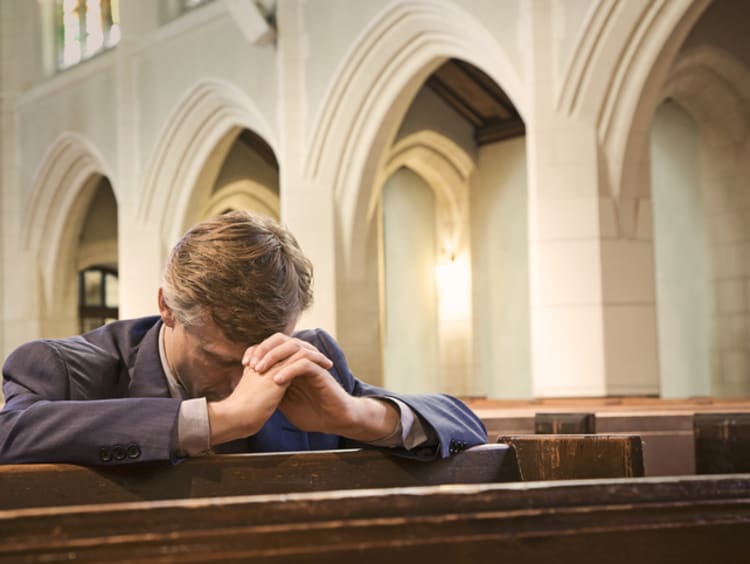 Man bows his head to pray in church for forgiveness