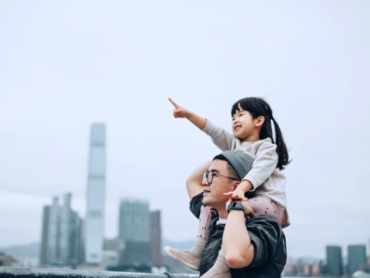 girl sitting on fathers shoulders pointing ahead of her