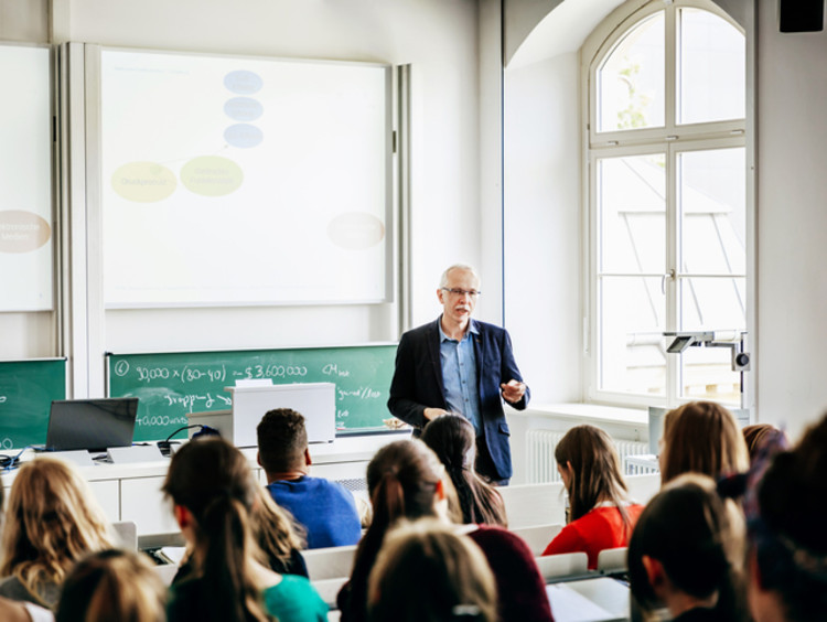 Professor teaching students at front of lecture hall