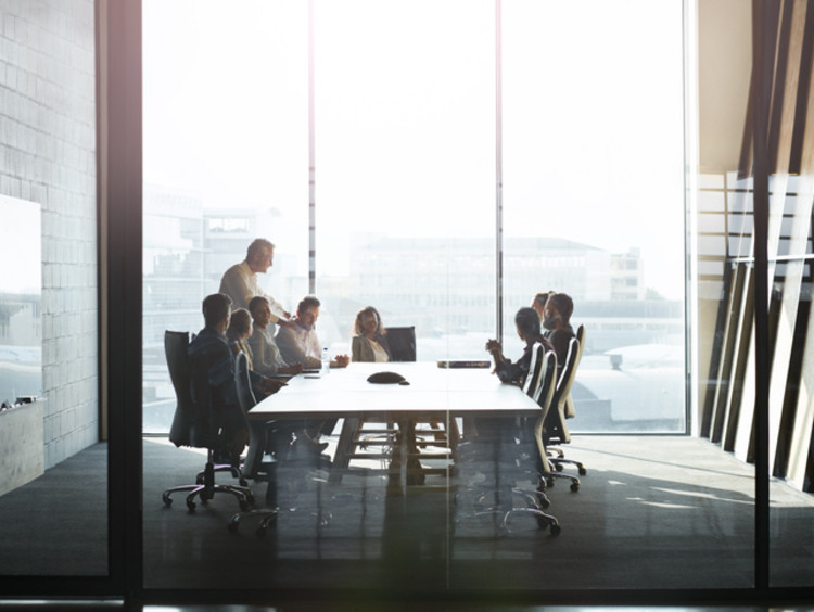 Men and women gathered around table in board room