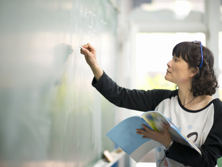 teacher writing on a chalkboard in the classroom