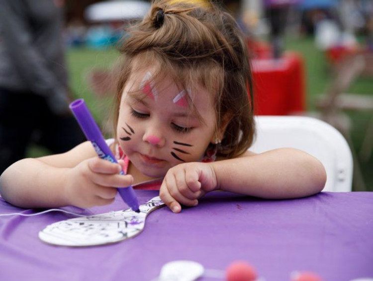 Little girl drawing on paddle ball with marker