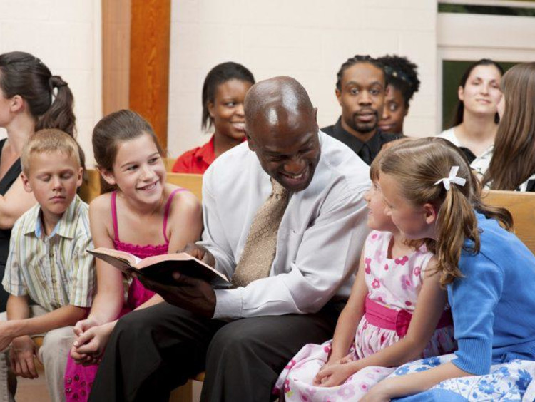 A man reading the Bible to a group of children