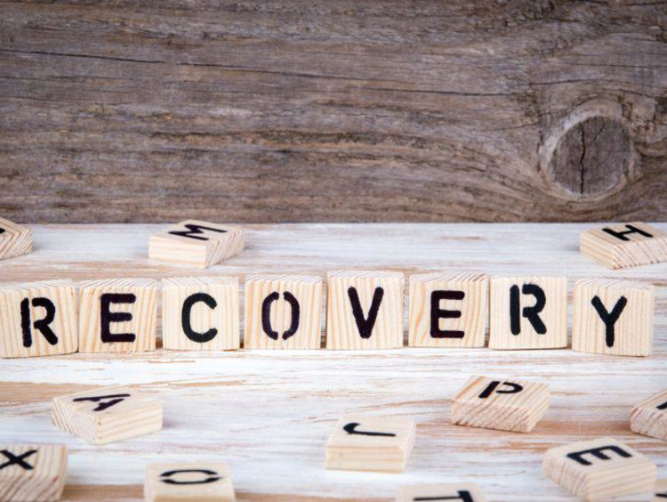 Letters on upright wood squares spell out recovery