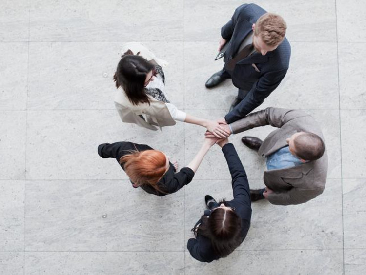 Business leaders all put their hands in the center