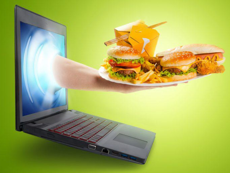 A hand with food reaching out of a computer screen