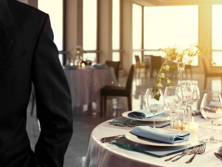 person in a suit standing in front of a hotel dinner table