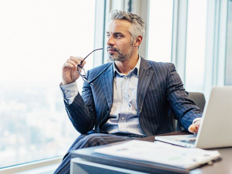 man with glasses looking out a window