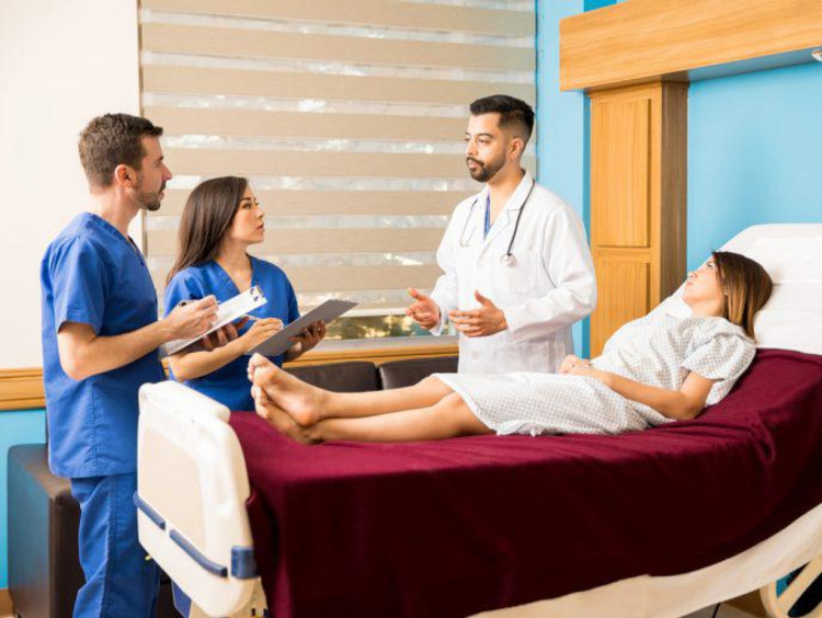 nursing students talking next to a patient