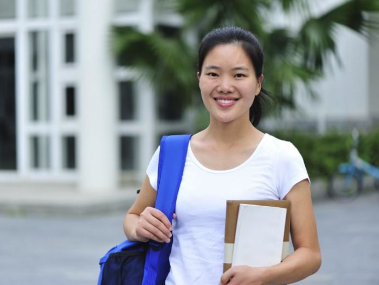 girl holding notebook and wearing backpack smiling
