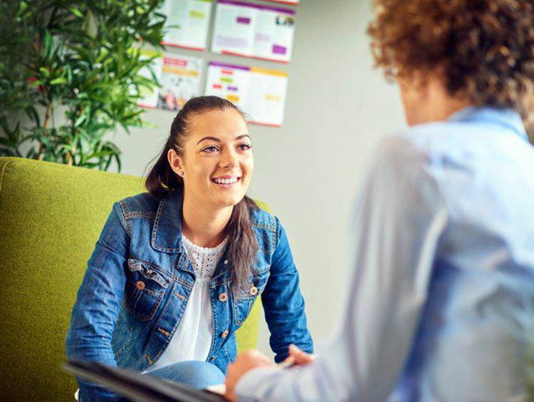 High school counselor sits across a smiling female student