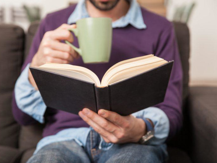 A man reading a book with a cup of coffee