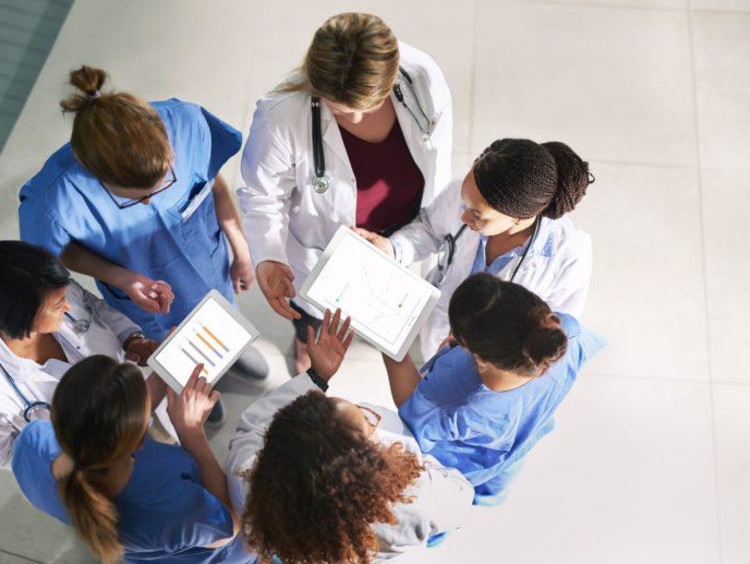 A team of nurses standing in a circle with their hands placed in the center.