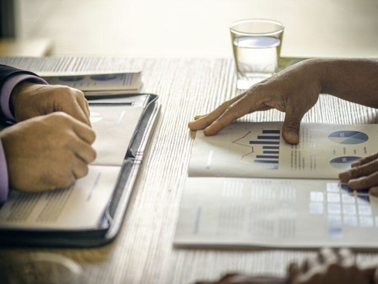 Health systems manager presents reports to another person at a table