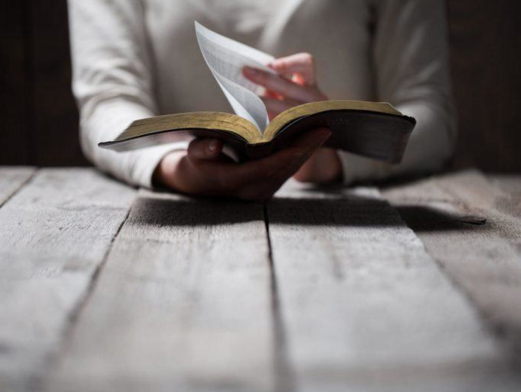 person flipping the page in a bible