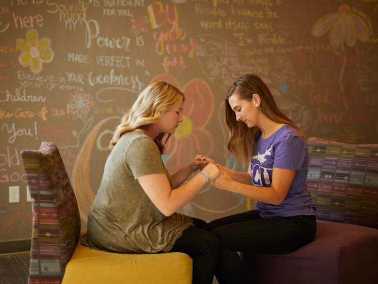 Two female students pray together